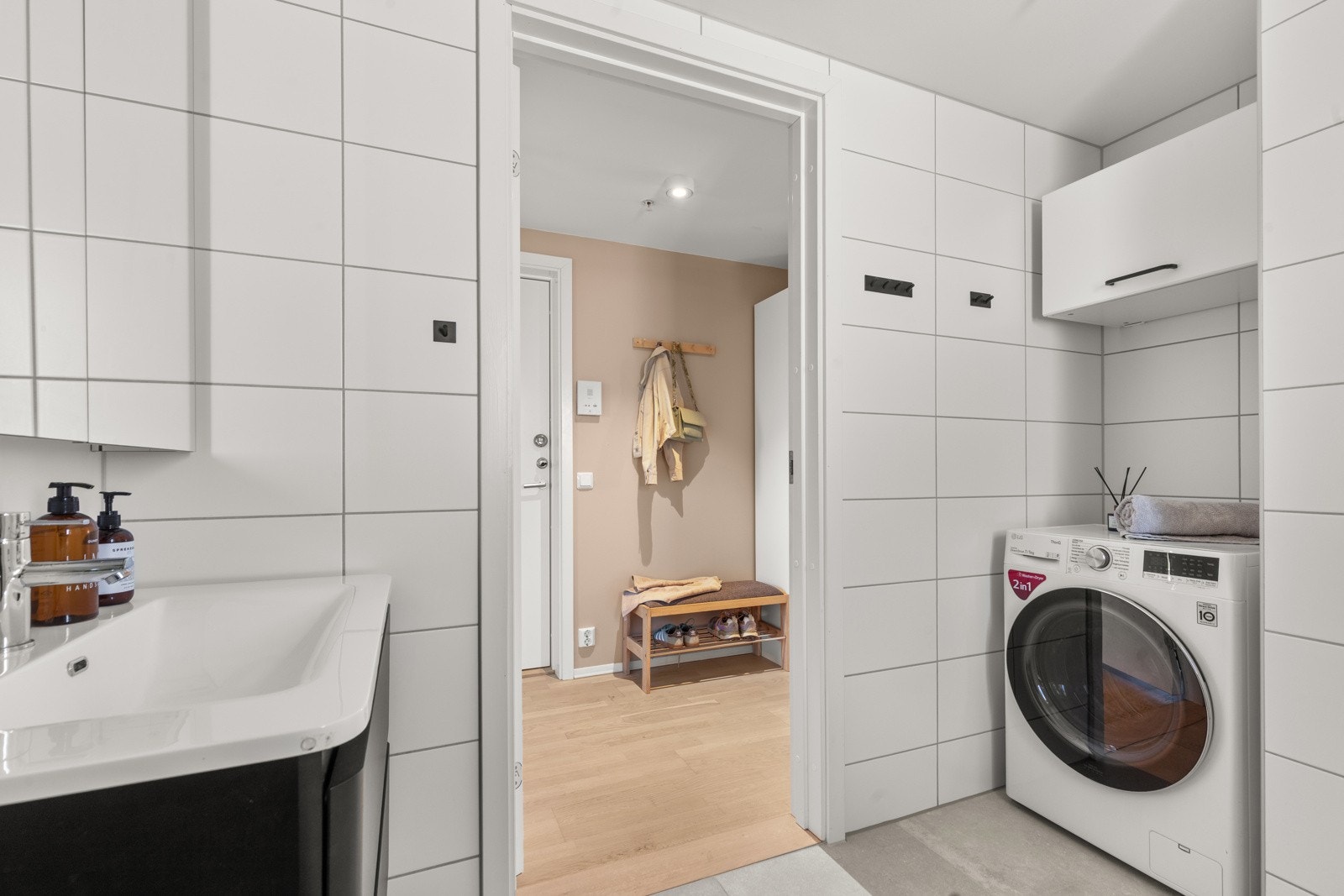 Praktisk nisje med opplegg for vaskemaskin. Vegghengt overhylle i nisje sørger for praktisk oppbevaring av f. eks. vaskemidler. Galleribilde