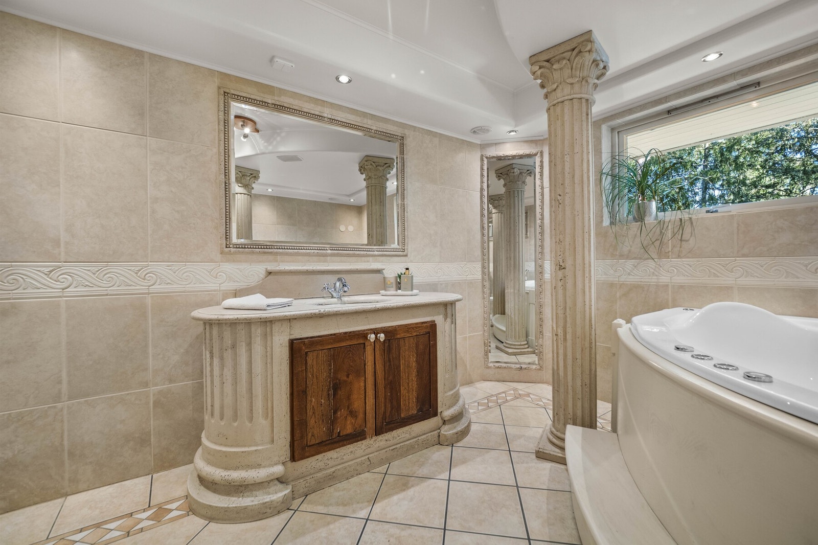 På badet er det innfelte speil og et elegant servantskap i samme stil som søylene. Galleribilde