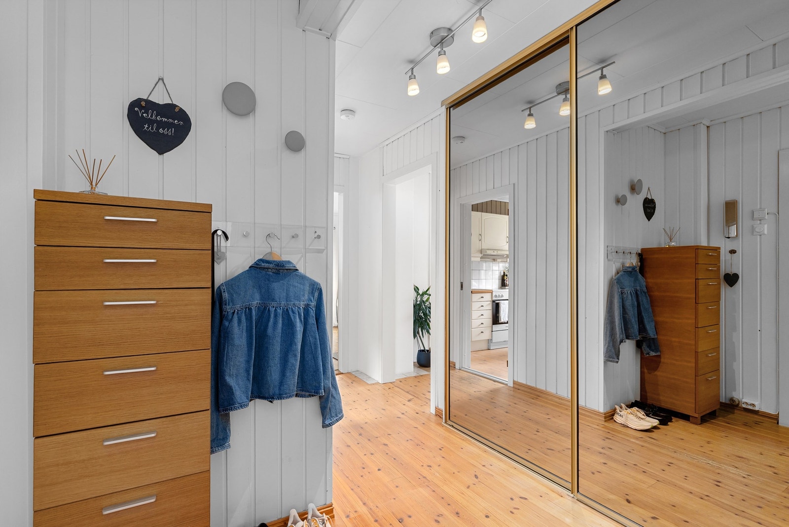 Lys og innbydende entré med plass til å sette fra seg sko og henge fra seg yttertøy i stor skyvedørsgarderobe Galleribilde