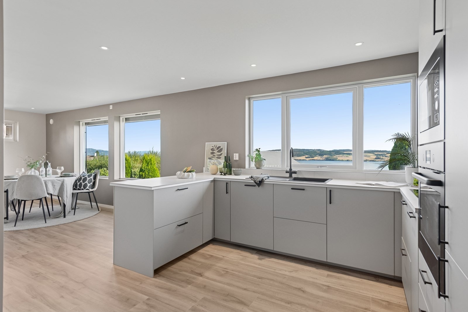 Stilren kjøkkeninnredning (1. etg.) med laminerte skrog, glatte fronter og flislagt benkeplate med kjøkkenkum. Fantastisk utsikt mot Mjøsa! Galleribilde