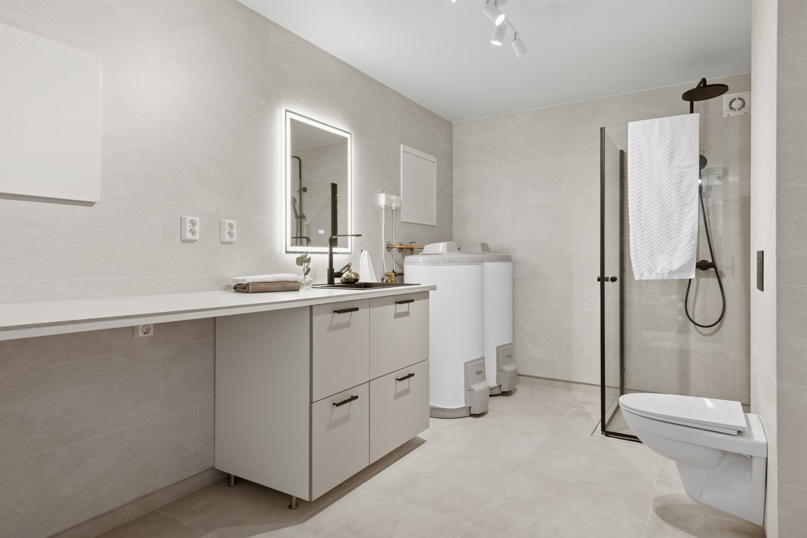 Bad/vaskerom utstyrt med servant med underskap, dusjvegger og vegghengt wc. Ventilasjonen består av mekanisk avtrekk med tilluft ved dør. Galleribilde