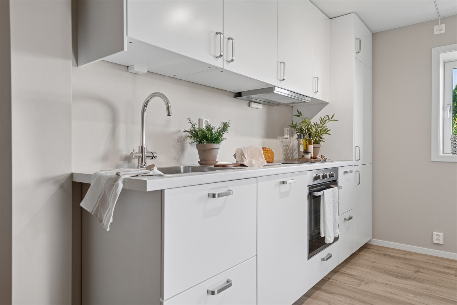 Lys og fin kjøkkeninnredning (u.etg.)med laminerte skrog, glatte fronter og laminert benkeplate med kjøkkenkum. Galleribilde