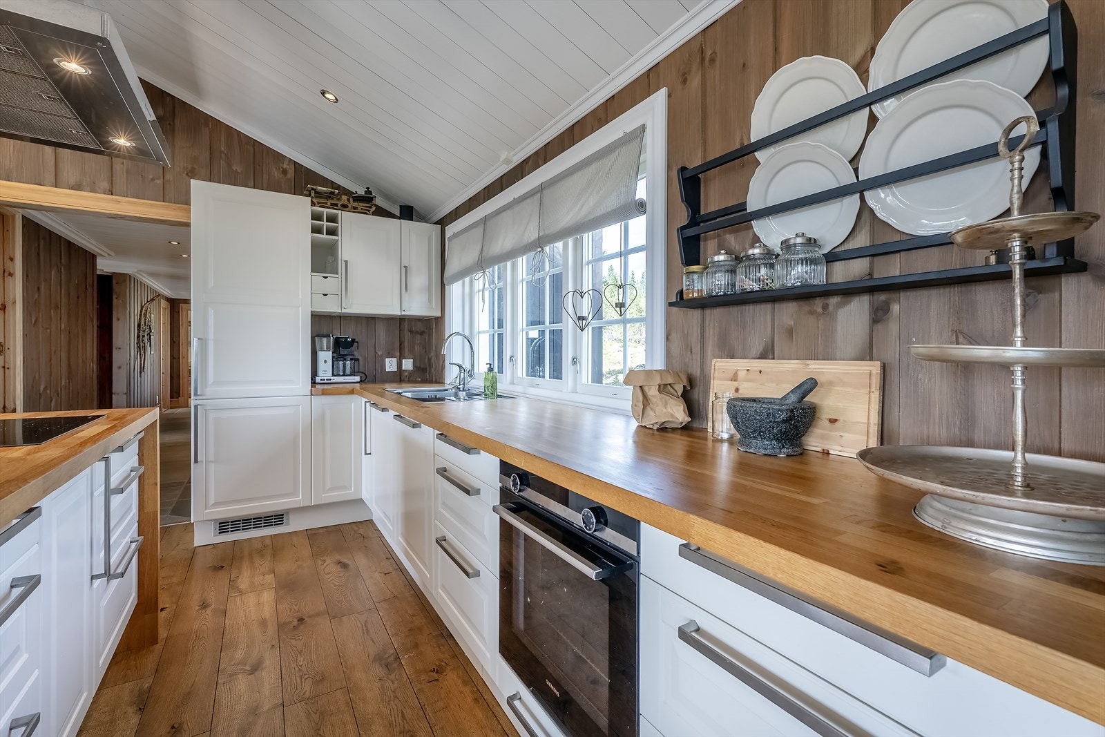 Tidløs kjøkkeninnredning med kjøkkenøy og integrerte hvitevarer, innrammet av benkeplater i eik Galleribilde