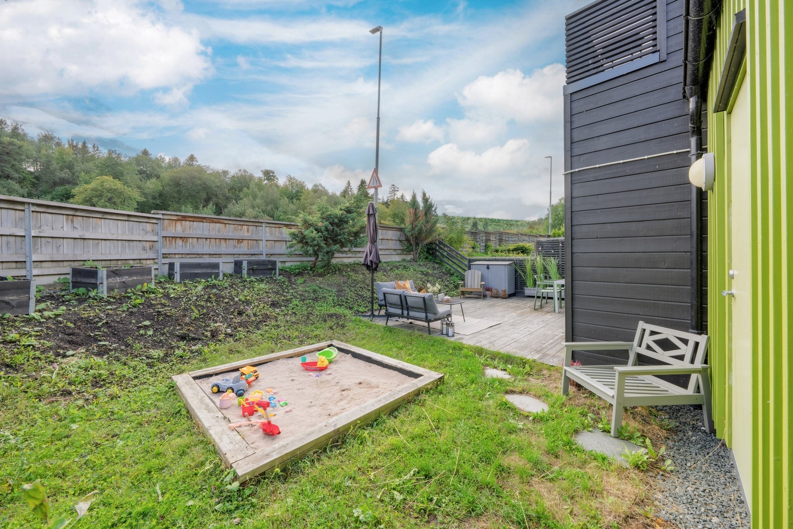 Kjekt med sandkasse for barna. Her er det god plass til å plante fargerike blomster og busker. Galleribilde