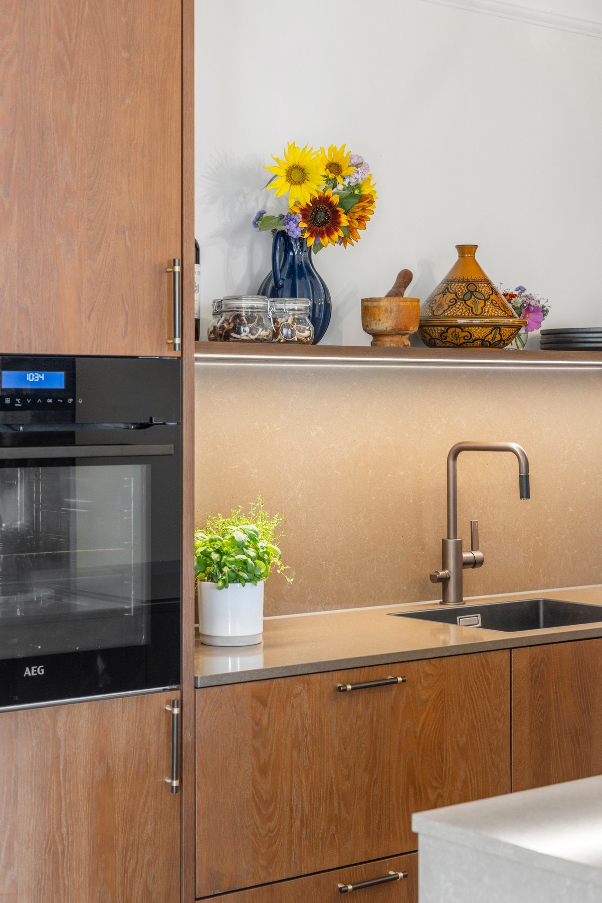 Komposittplate på vegg over vask som matcher benkeplaten understreker kjøkkenets gjennomførte stil. Galleribilde