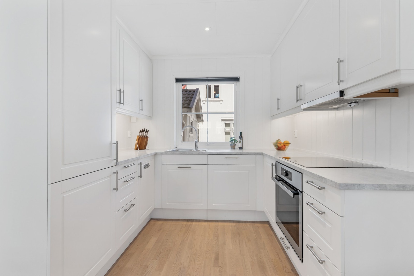 Innredningen har integrerte hvitevarer, herunder kjøl/fryseskap, oppvaskmaskin, induksjonstopp og stekeovn Galleribilde