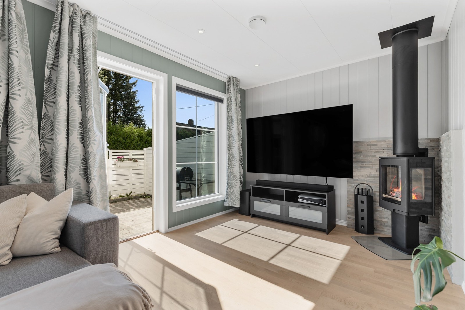 I hjørnet er det installert en stilren peisovn som skaper både hygge og behagelig varme på kjølige dager Galleribilde