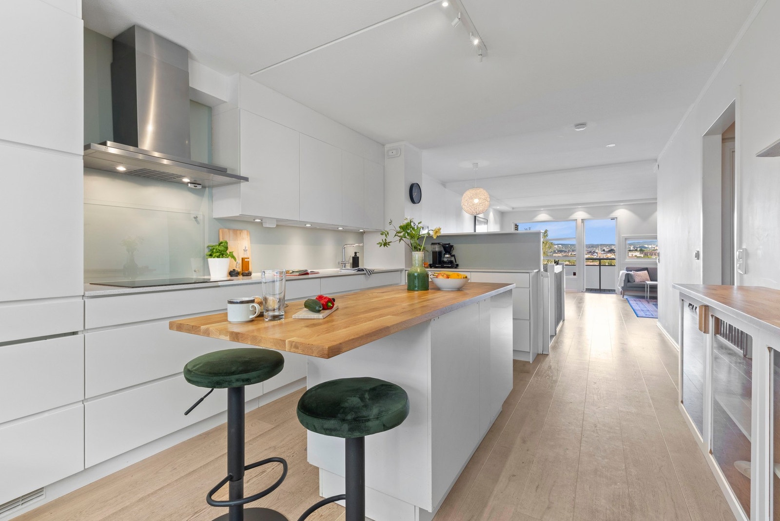 Kjøkkenet glir sømløst over i oppholdsrommet, med byens silhuett som en del av rammen. Galleribilde