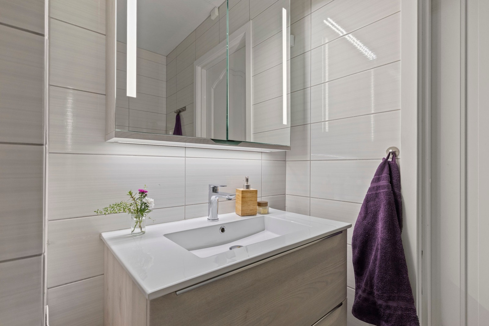 Badet er innredet med moderne servantinnredning, speilskap med belysning og praktiske oppbevaringsmuligheter. Galleribilde