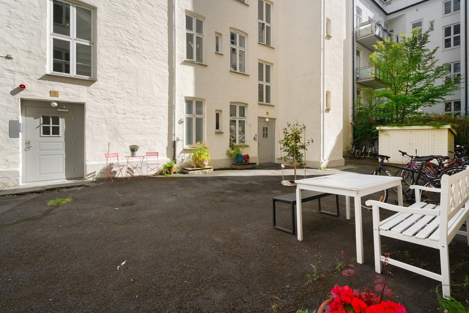 Hyggelig asfaltert gårdsrom med sittegrupper og sykkelparkering. Galleribilde