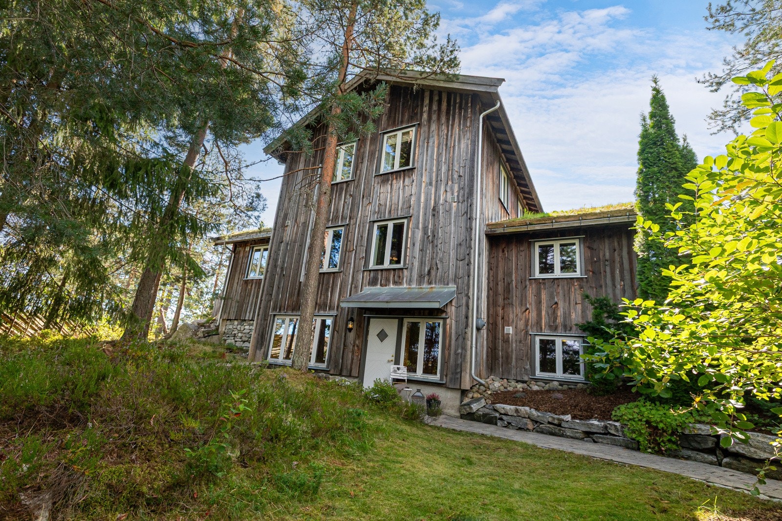 Fra en hyggelig sti ned fra gårdsplassen kommer vi ned til utleiedelens del. Utleiedelen har et hyggelig uteområde og det er lagt belegningsstein som gir en flott gangvei til inngangspartiet. Galleribilde