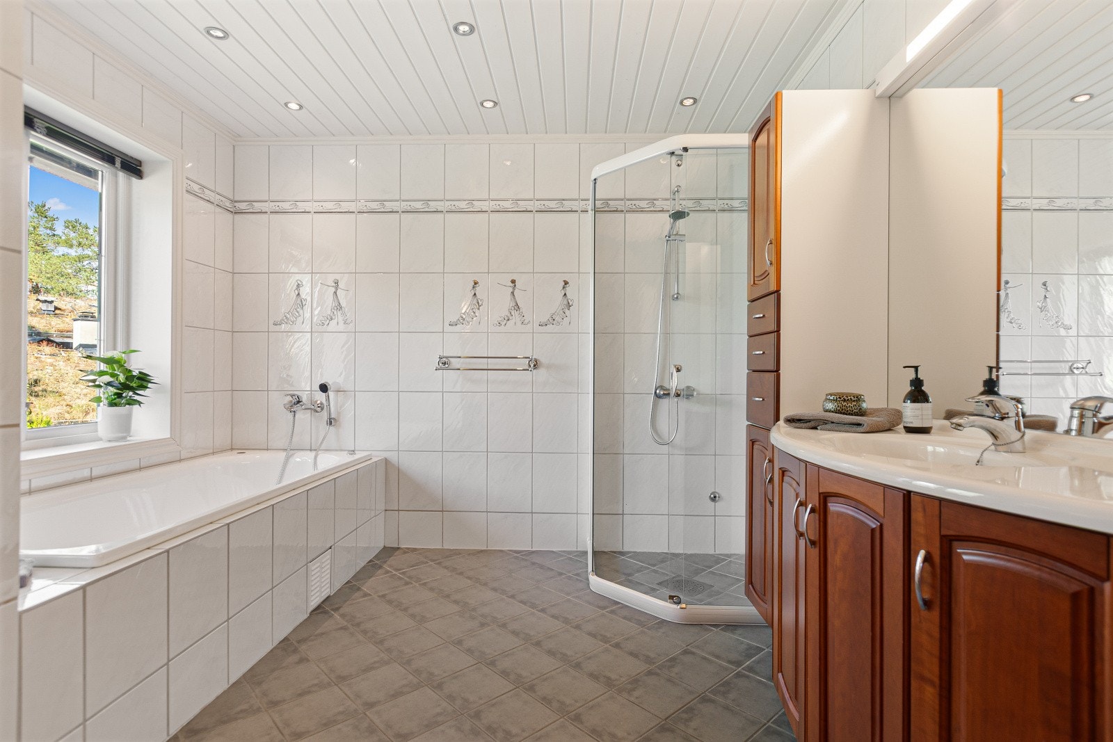 Badet i andre etasje er flislagt med downlights i himling. Badet er innredet med badekar, dusjnisje med tett sokkel og toalett. Galleribilde