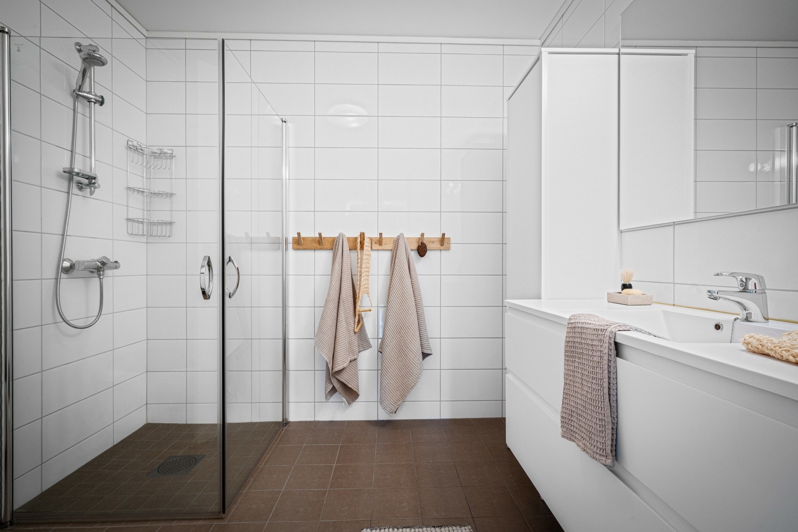 Moderne bad med fliser og varmekabler, dusj med glassdører og servant med underskap - en funksjonell og stilren løsning. Galleribilde