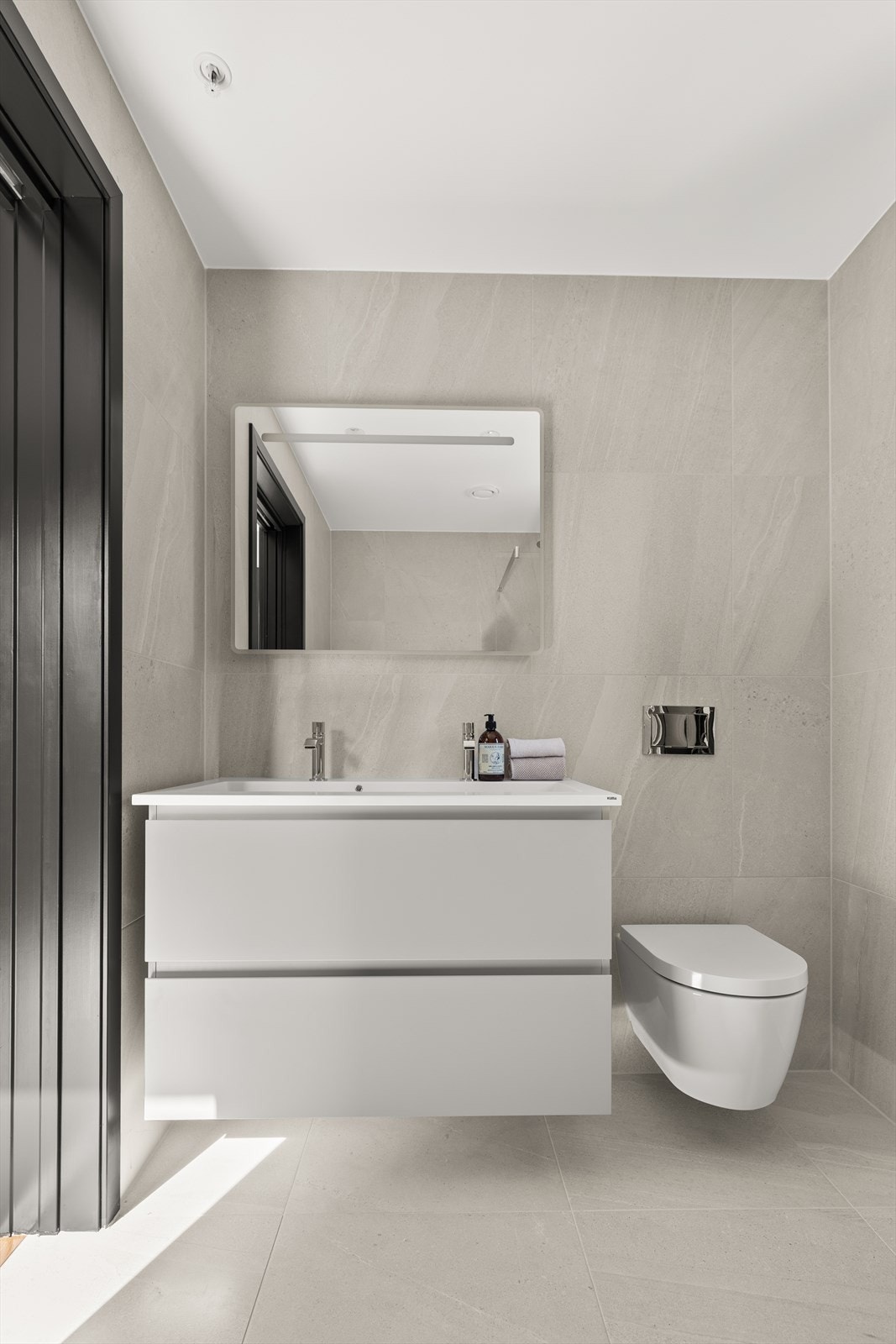 Moderne baderomsinnredning med heldekkende hvit servant, to armaturer og lysspeil Galleribilde