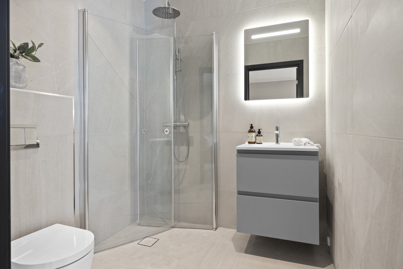 Badet er pent flislagt med god standard. Vegghengt toalett, baderomsinnredning med lysspeil og dusjhjørne med regnfallsdusj Galleribilde