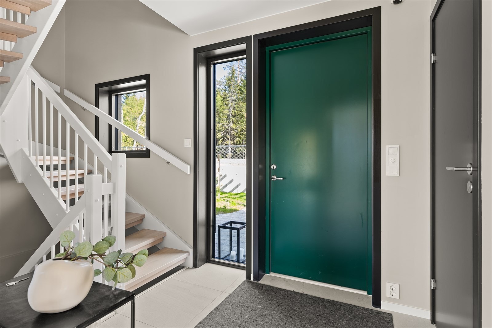 Hall i 1. etasje med 60x60 cm. fliser på gulv, elektriske varmekabler og downlightsbelysning. Inngangsdør med sidefelt i glass Galleribilde