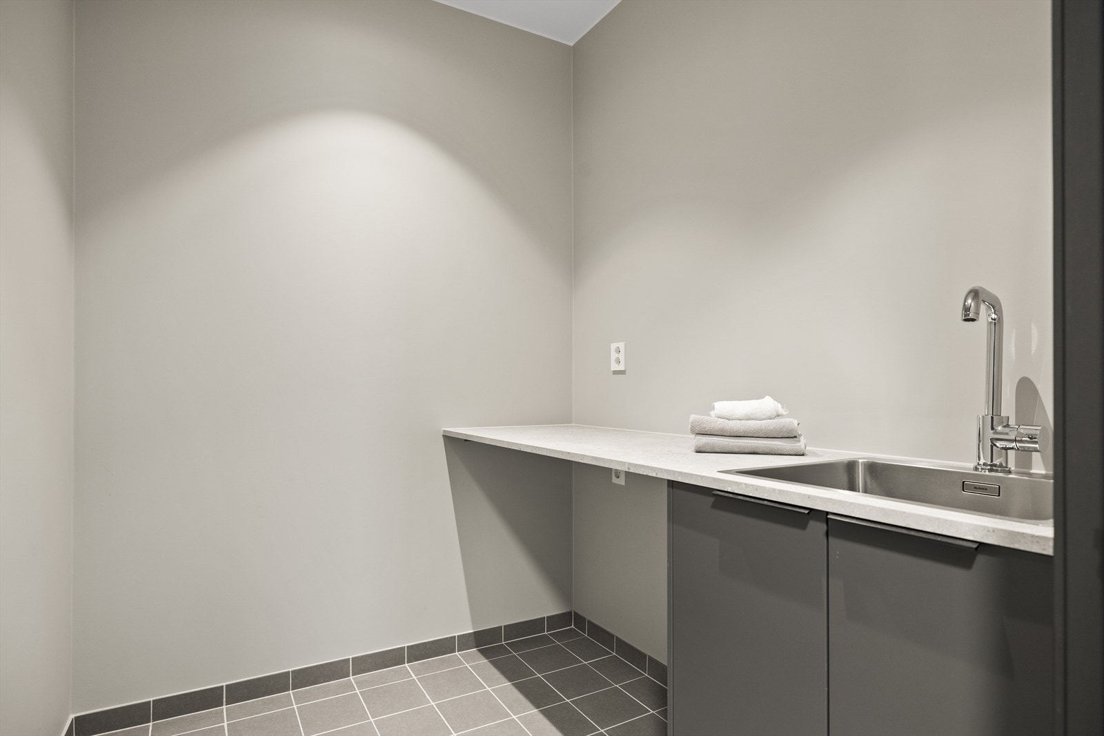 Praktisk vaskerom i kjelleretasje med flislagt gulv og malte veggflater Galleribilde