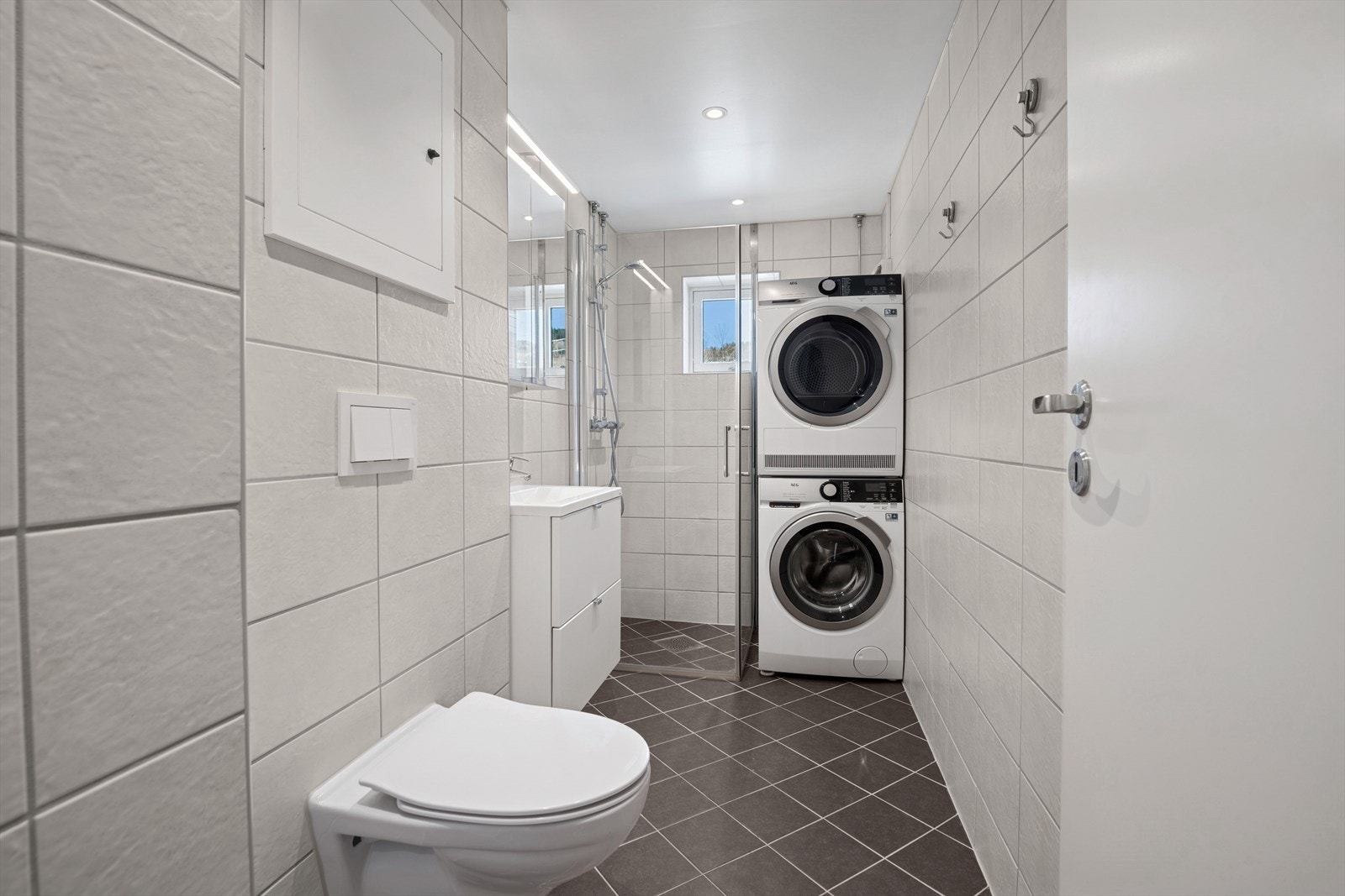 Rommet er et kombinert bad/vaskerom med flislagte overflater og komfortabel gulvvarme. Galleribilde