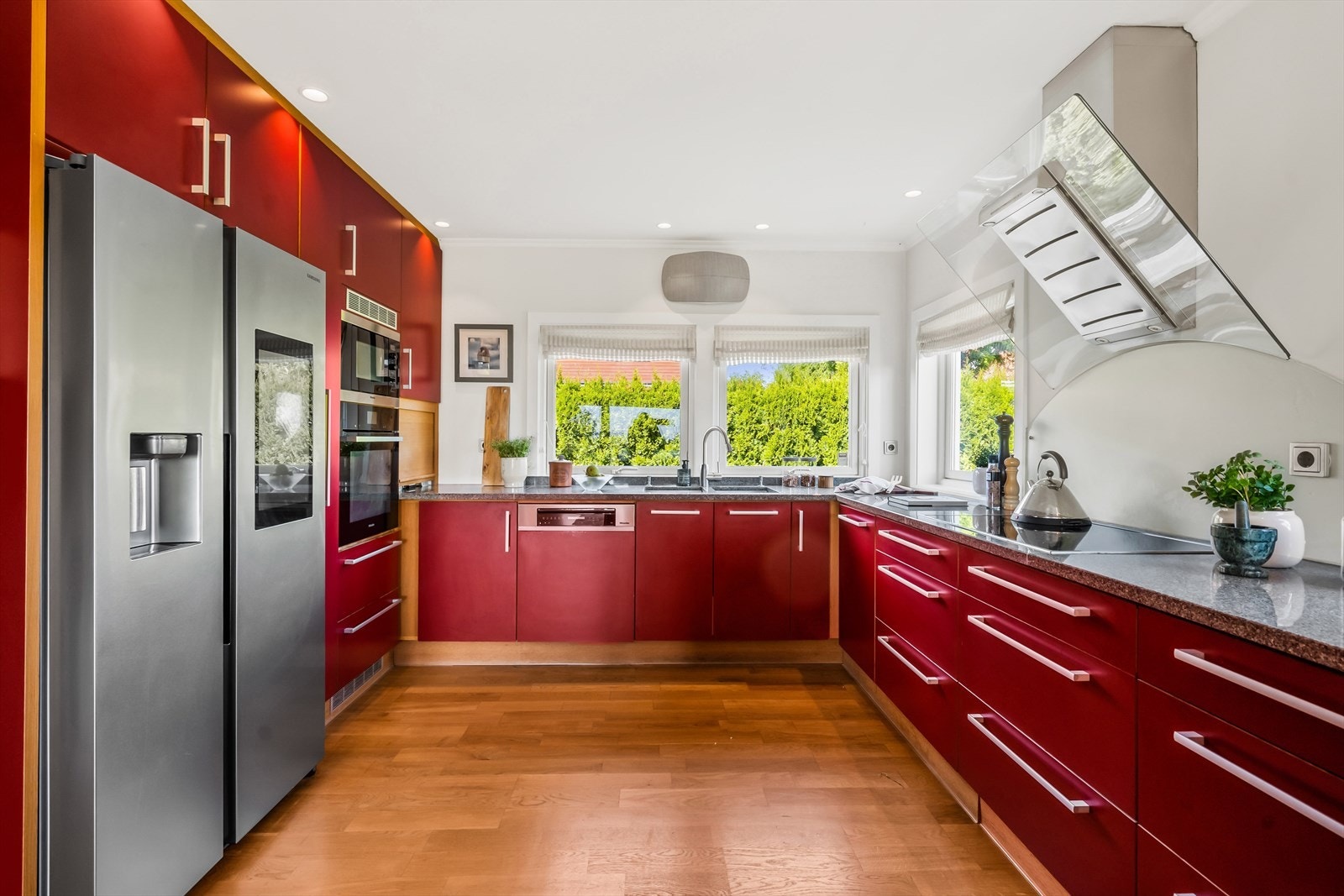 Stilig innredning med glatte, røde fronter og benkeplate i stein. Galleribilde