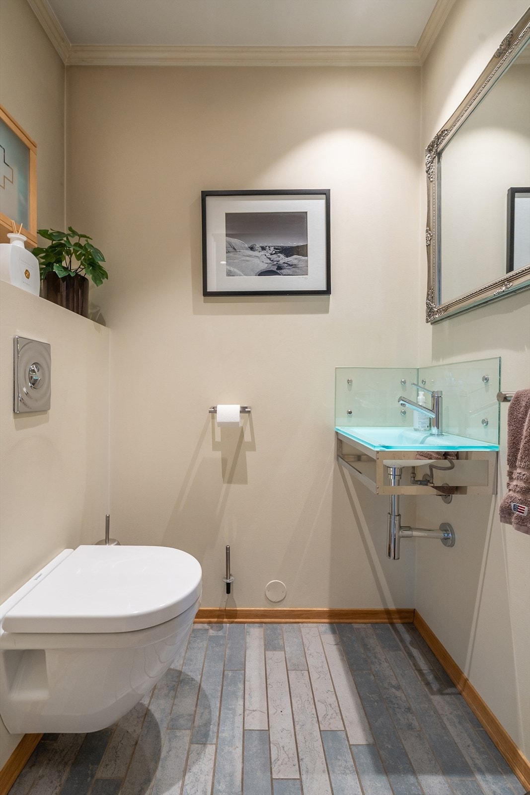 Praktisk, separat toalett med adkomst fra gangen. Utstyrt med veggmontert toalett og servant med glassoverflate og ettgreps armatur. Galleribilde