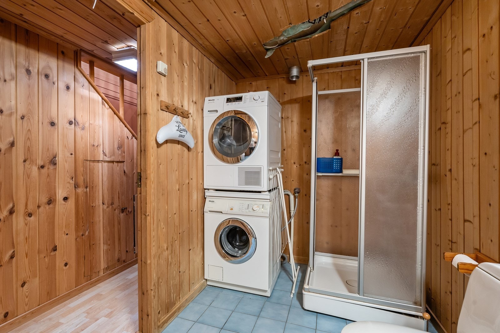 Badet er innredet med gulvstående toalett, dusjkabinett og servant med ettgreps armatur. Opplegg for vaskemaskin og tørketrommel. Galleribilde