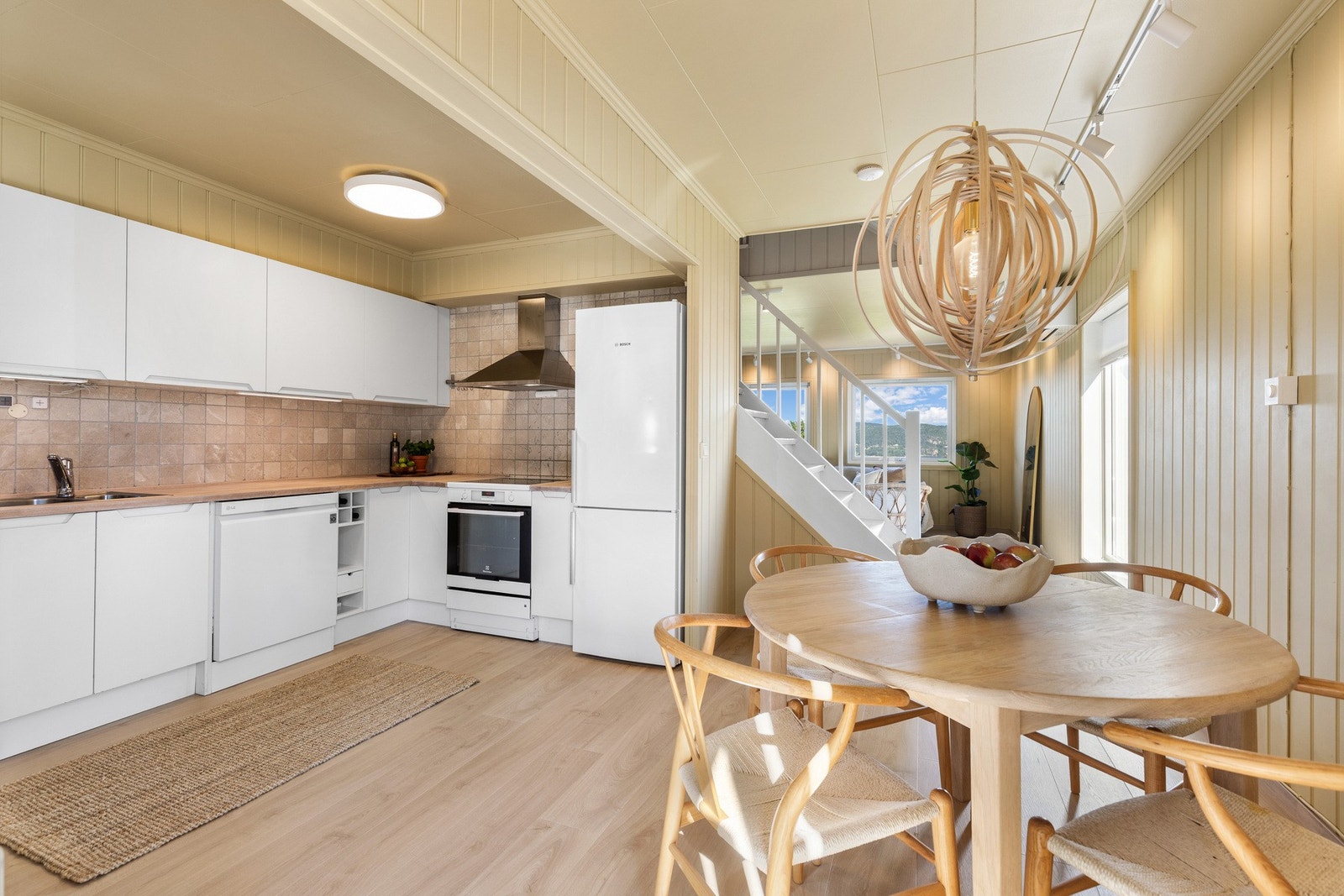 Lyst og moderne kjøkken med integrerte hvitevarer, spiseplass og åpen løsning mot stue. Galleribilde