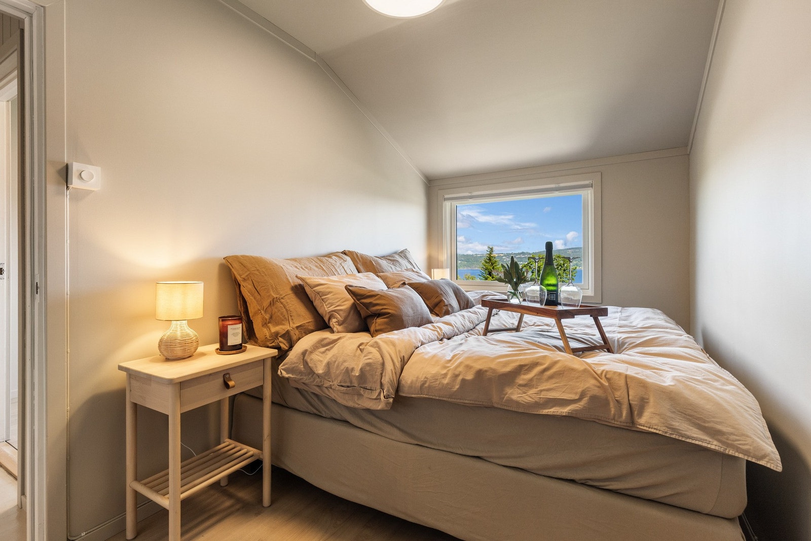 Lyst og koselig soverom med skråtak og stort vindu med utsikt. Galleribilde