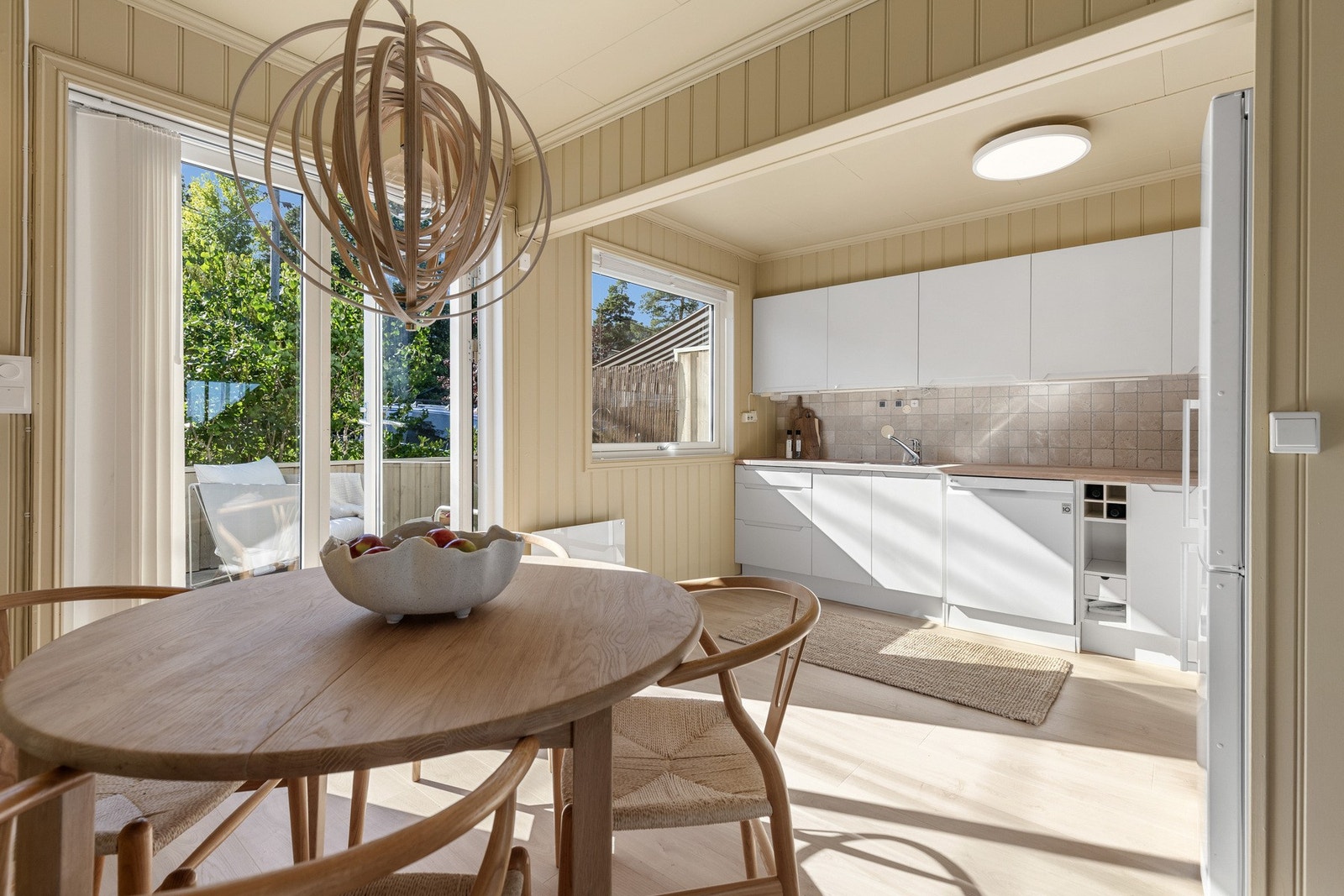 Lyst og åpent kjøkken med store vinduer, spiseplass og direkte utgang til en solrik uteplass. Galleribilde