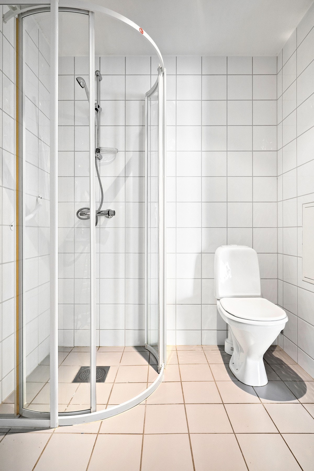 Videre er rommet innredet med gulvstående toalett og dusjhjørne med skyvedører Galleribilde