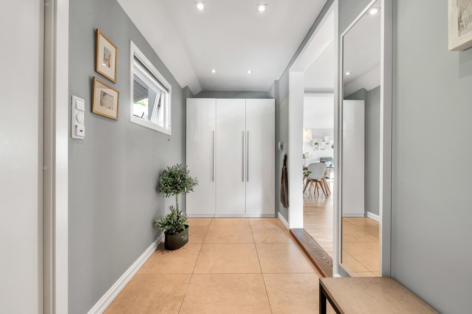 Entreen har stilrene overflater og god takhøyde. Gulvet har store fliser og veggene er gråmalte med listefri overgang til himling. I himlingen er det downlights. Galleribilde