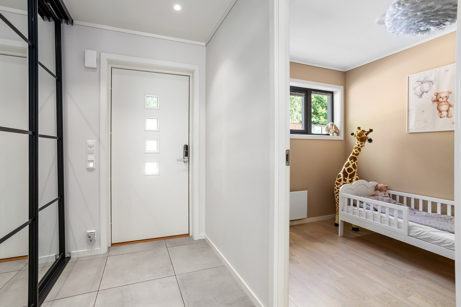 Den lyse og romslige entreèn har en praktisk og takhøy tre-dørs skyvedørsgarderobe med dører av speil hvor klær og skotøy kan ryddes pent vekk. Skyvedørene har moderne profiler i sort som setter et ekstra moderne preg til rommet. Galleribilde