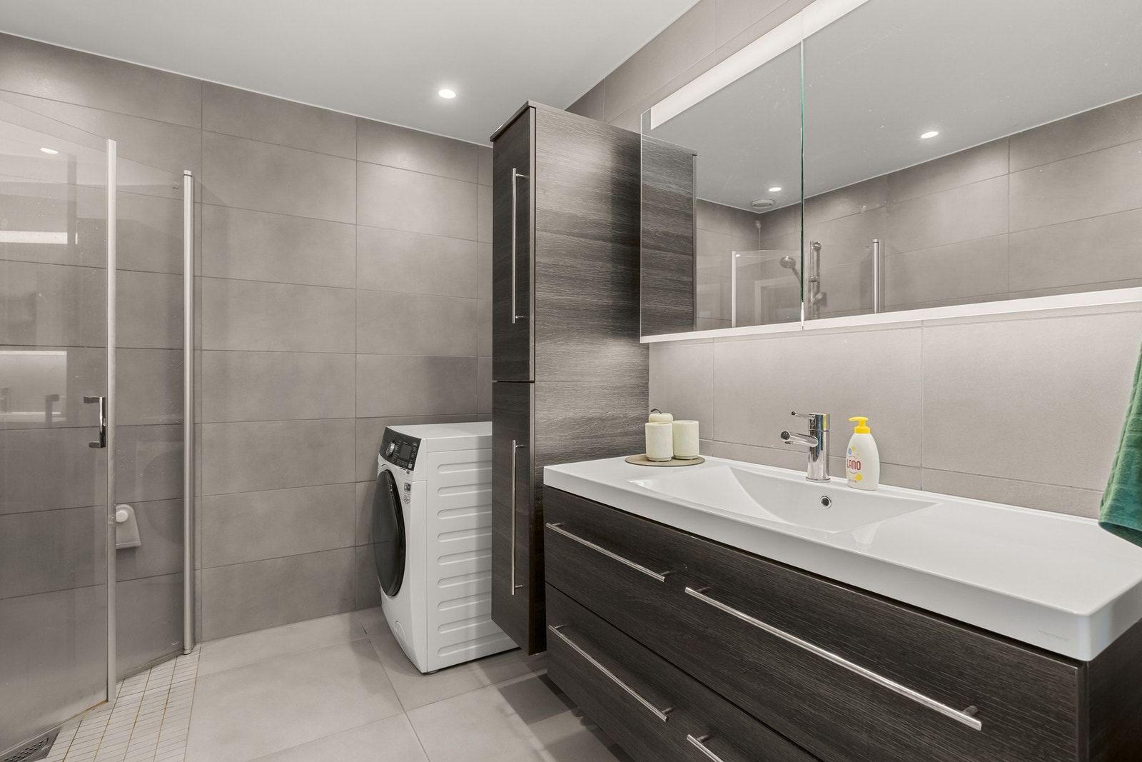 Stilrent baderom med flislagte gulv og vegger, samt malte takflater med downlights som gir en behagelig belysning. Galleribilde