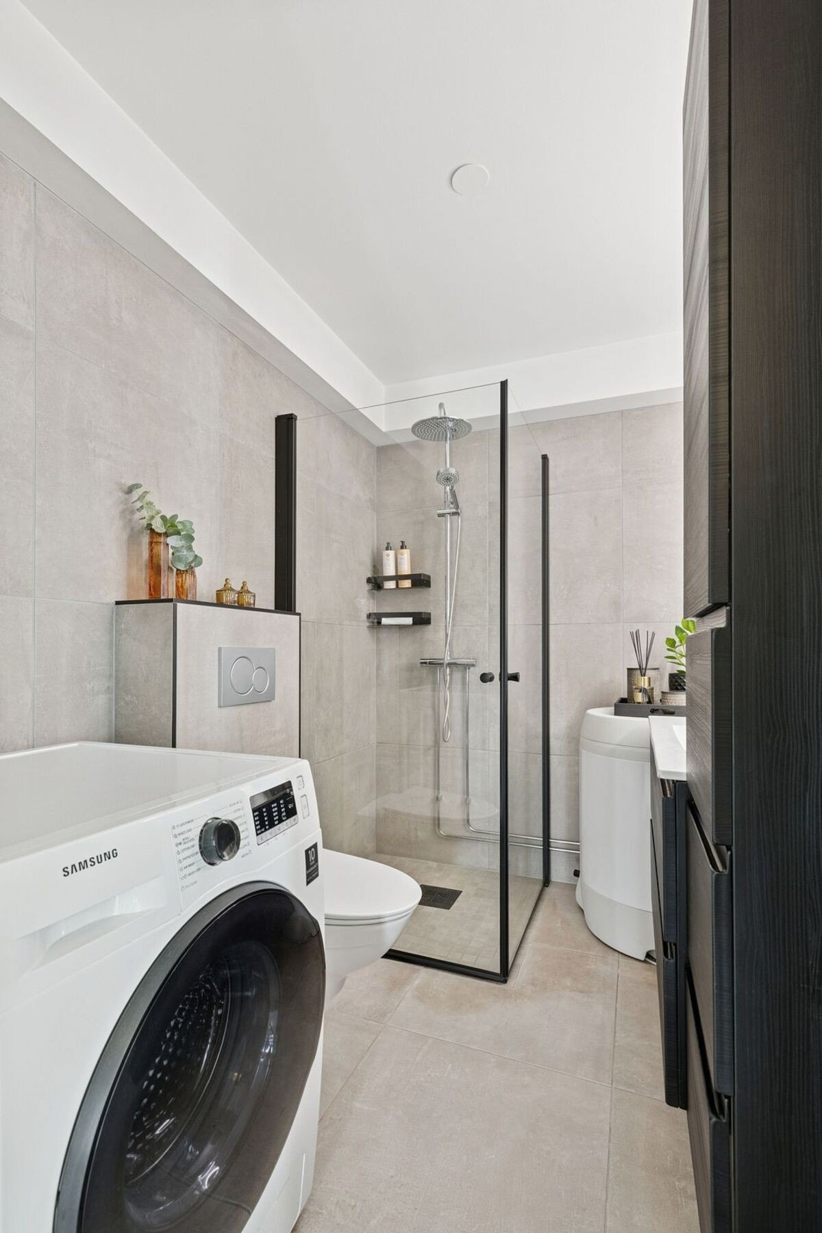 Badet ble lekkert oppusset i 2021. Store fliser i lysegrå nyanser gir rommet et moderne uttrykk, elegant kombinert med mørke detaljer i innredninger og rustfritt stål i garnityr. Galleribilde