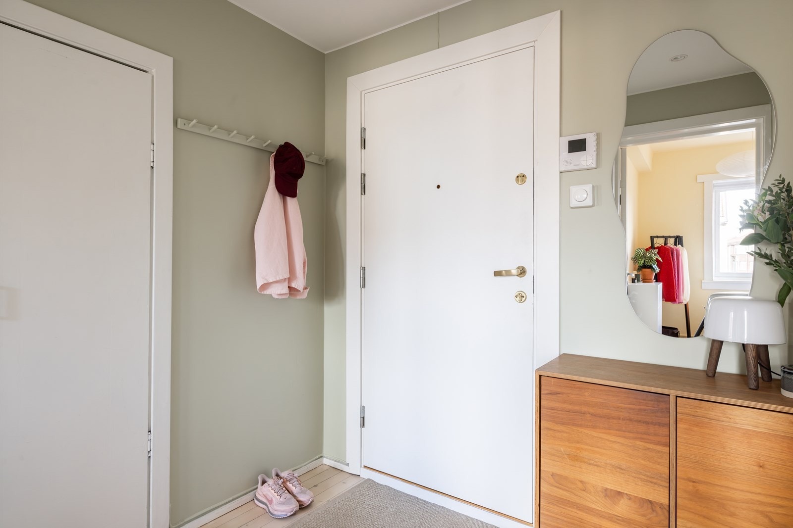 En innbydende entré med plass til å henge fra seg yttertøy og sko. Veggene er malt i en behagelig grønnfarge som gir et lunt og velkomment førsteinntrykk. Galleribilde