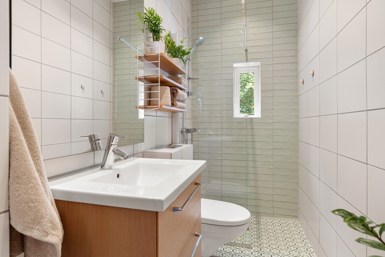 Flislagt bad med varmekabler, dusjnisje, veggmontert servantskap og toalett Galleribilde