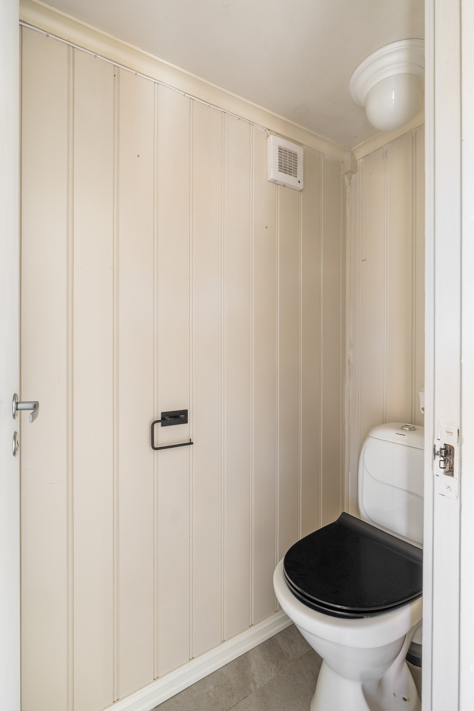 I entréen er det et separat toalettrom med fliser på gulv fra 2020 og malte mdf-plater på veggene. Galleribilde