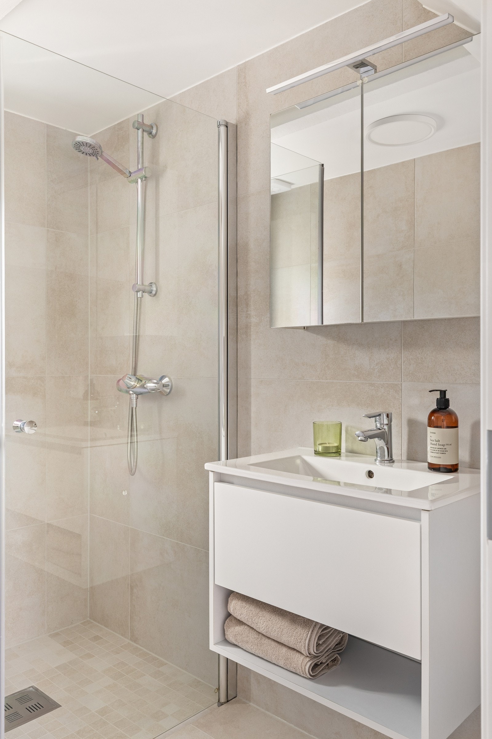 Badet er innredet med servant med oppbevaring, overskap med speil og lys, et dusjhjørne og opplegg til vaskemaskin. Galleribilde