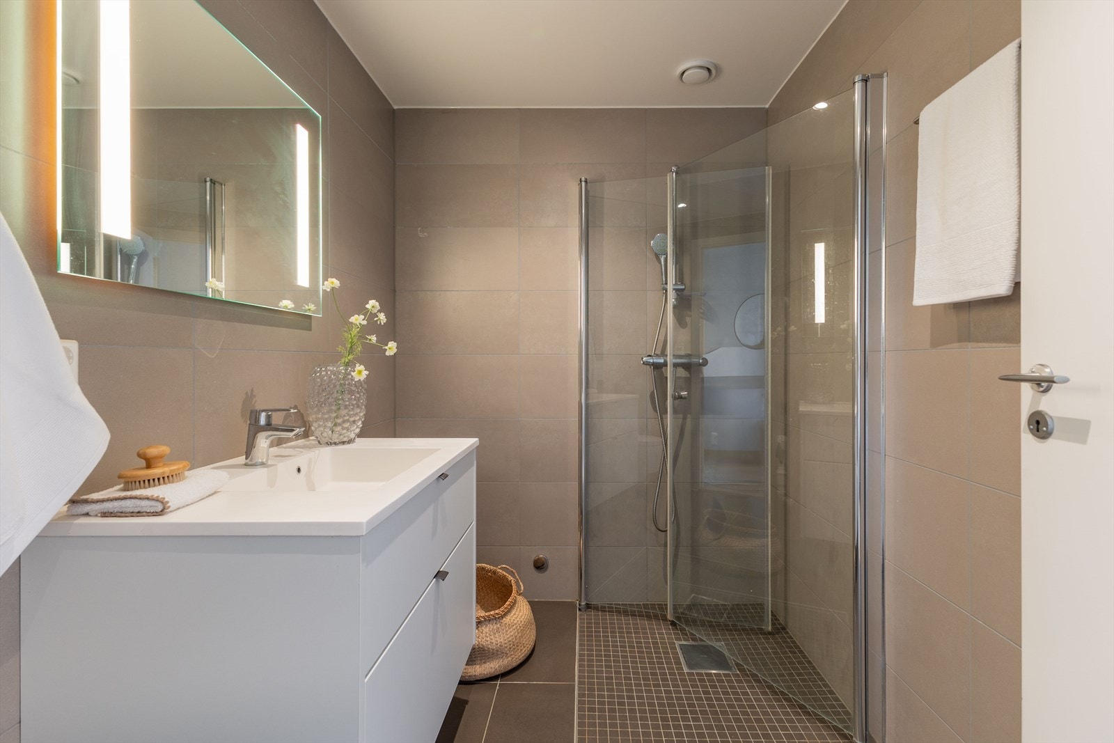 Rommet er utstyrt med dusjhjørne m/innfellbare glassdører, vegghengt toalett, baderomsinnredning og opplegg for vaskemaskin. Galleribilde