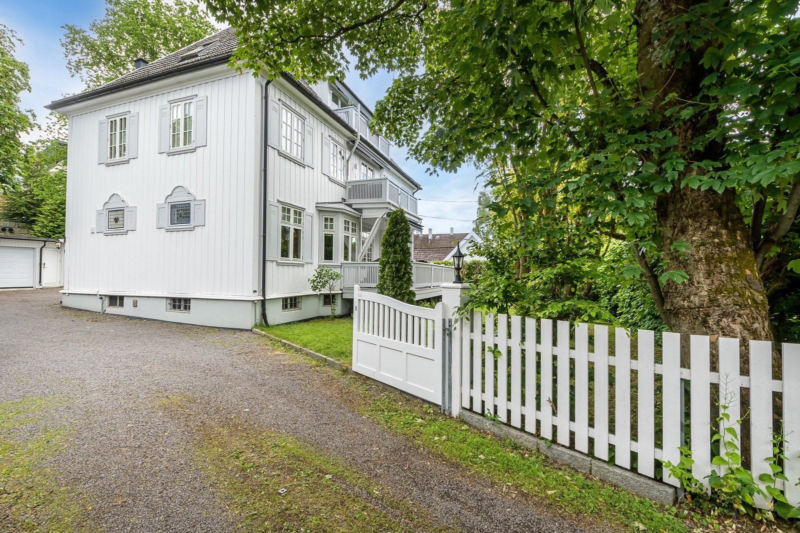 Klassisk bolig med innbydende fasade, hvit stakitt og skjermet hageadkomst. Galleribilde