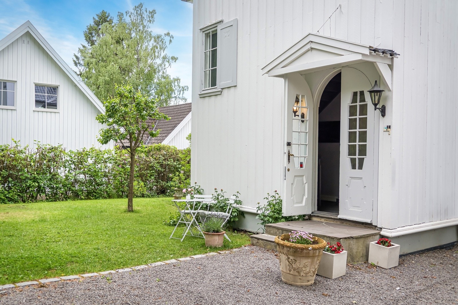 Sjarmerende inngangsparti med klassiske detaljer og hyggelig hage med plen, hekk og sitteplass. Det er plass til barnvogn rett utenfor inngangen til leiligheten. Galleribilde
