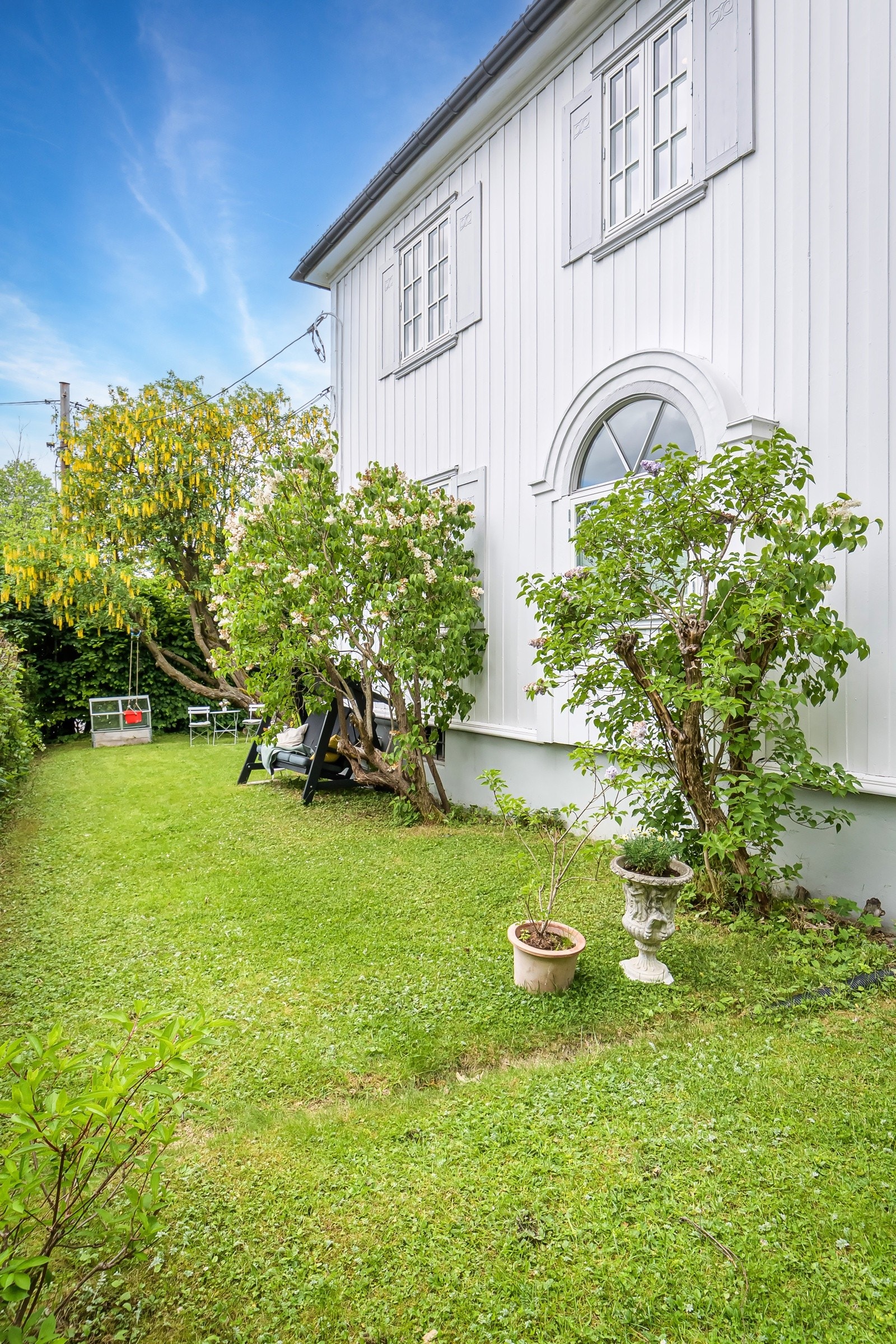 Grønn og skjermet hage med sittekroker og frodig beplantning, sydsiden av huset. Galleribilde