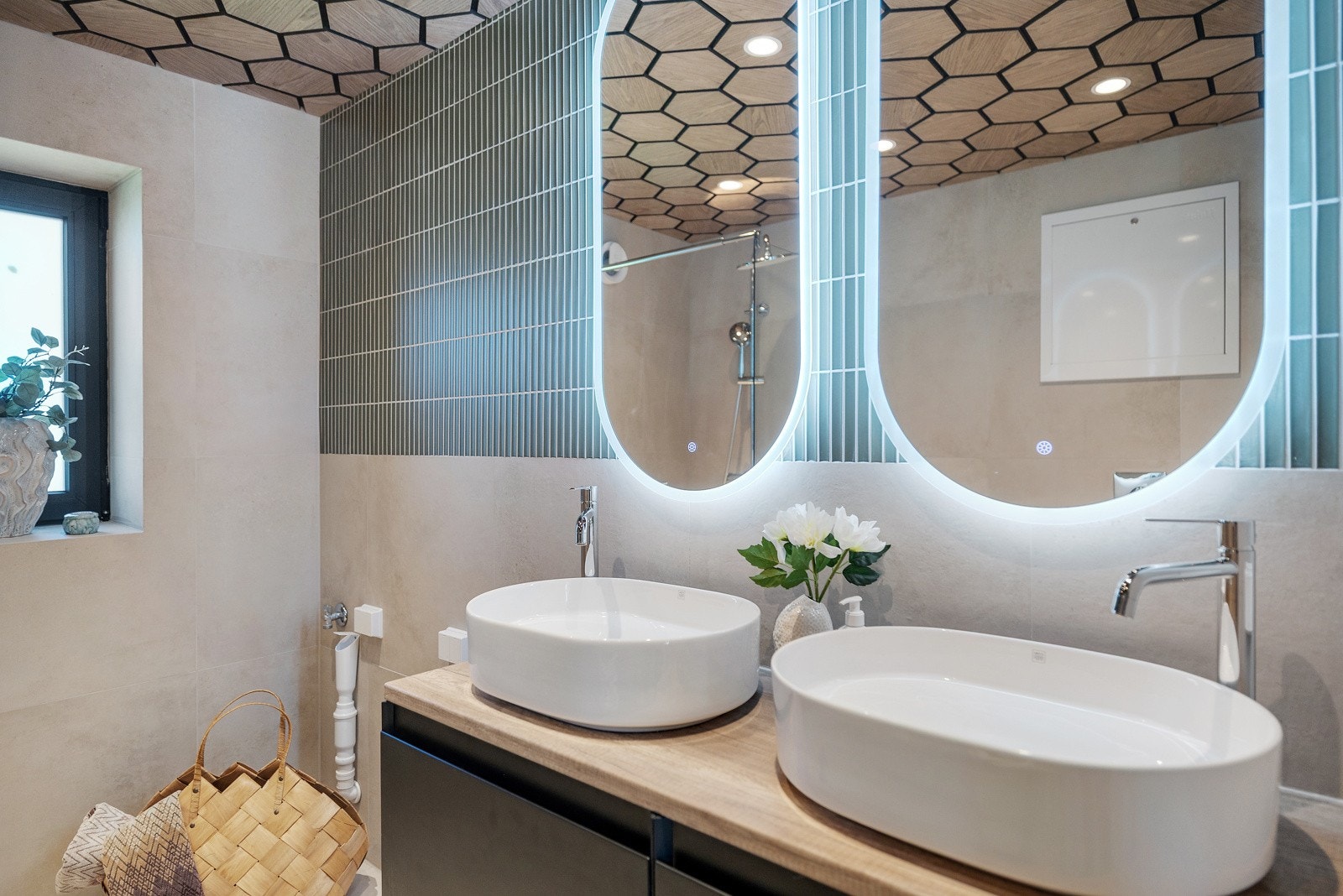 Laminat benkeplaten har to elegante servantboller som er plassert på benken, med to speil med integrert lysarmatur montert på veggen over servantene. Galleribilde