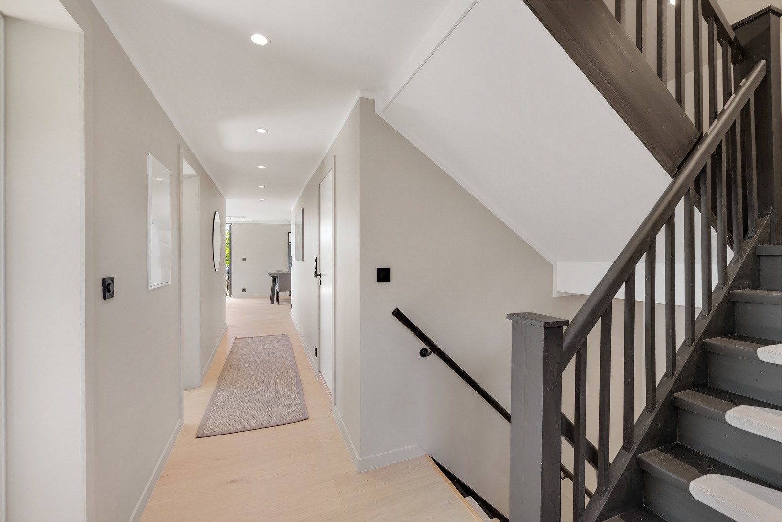 Lekker sort tretrapp mellom boligens etasjer utgjør en lekker kontrast mot den ellers lyse estetikken i rommet Galleribilde