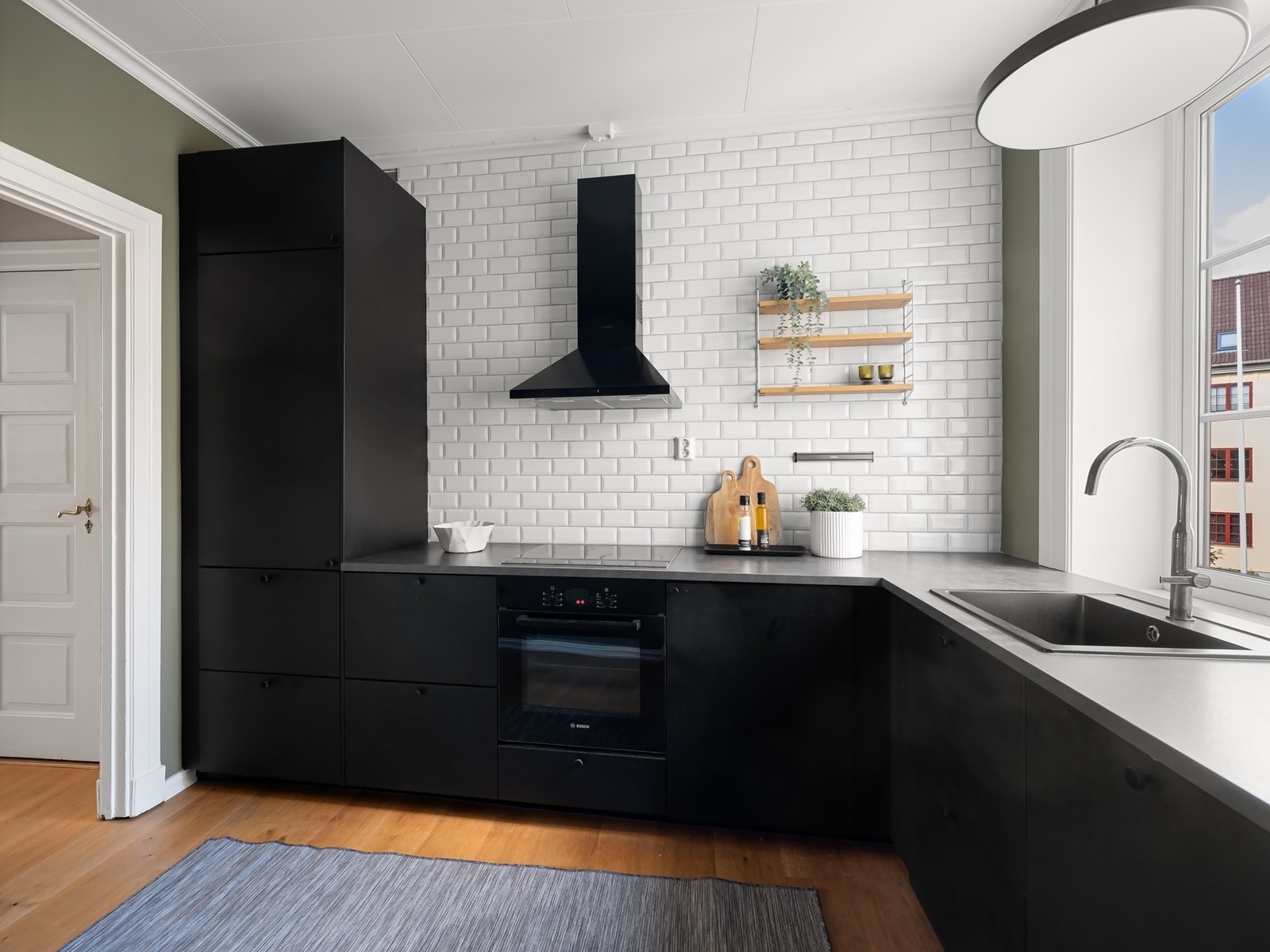 Stilrent kjøkken fra 2018 med sorte fronter, klassiske subway-fliser og laminat benkeplate. Medfølgende integrerte hvitevarer fra Bosch gir en helhetlig og funksjonell løsning. Galleribilde