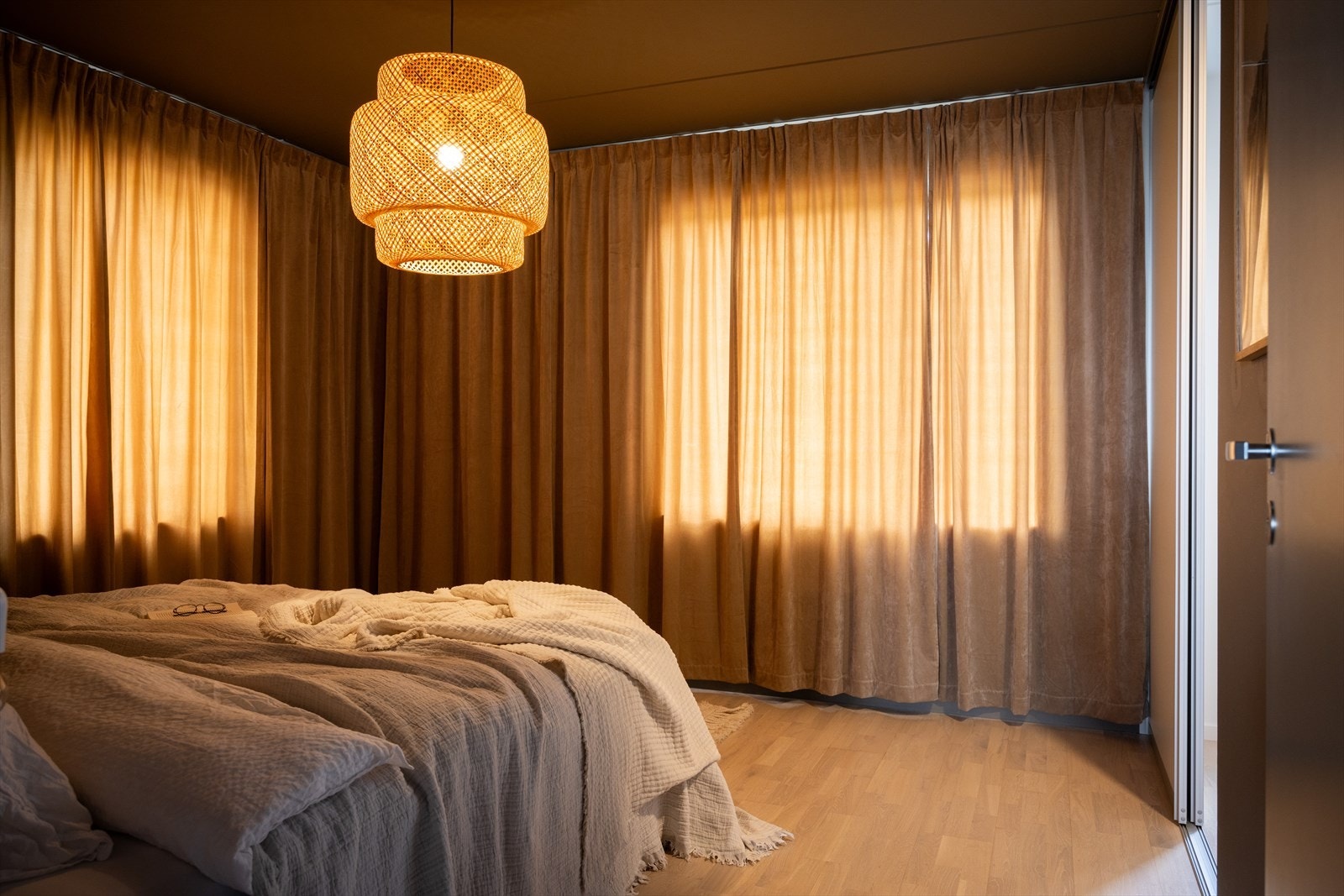 Rommet har gulv-til-tak gardiner i dus tone som skaper en lun og harmonisk stemning. Galleribilde