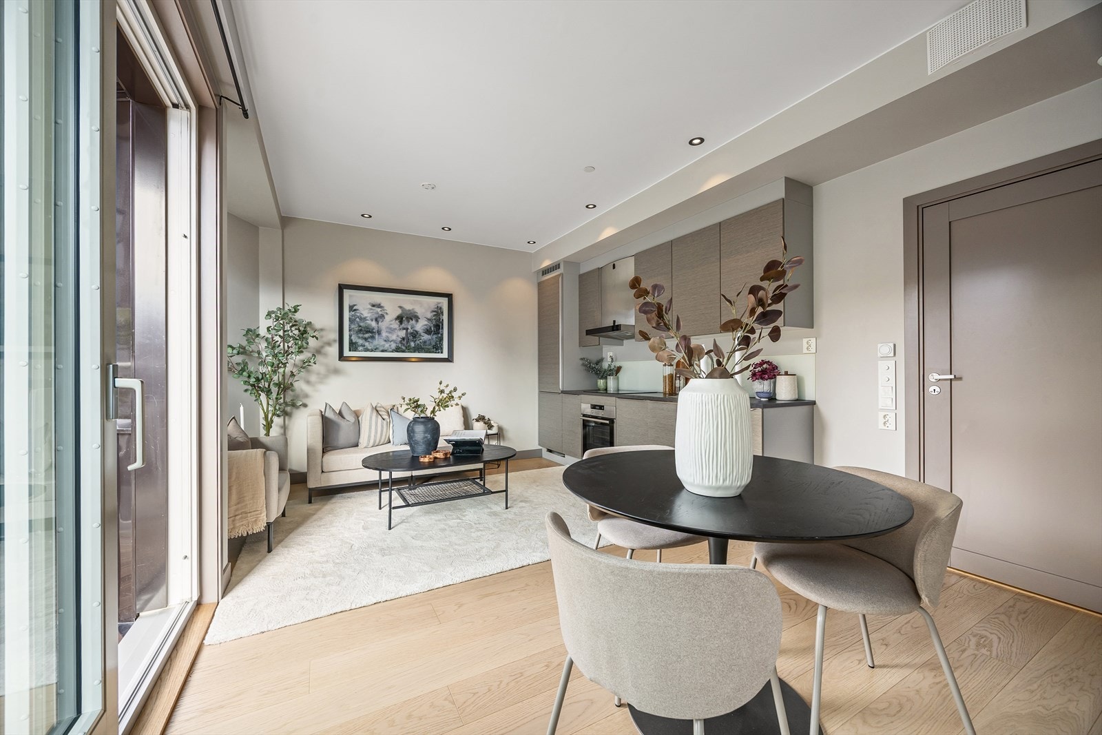 Leilighetens gode planløsning gir muligheter til å innrede i ulike soner med generøs sofagruppe og spisebord Galleribilde