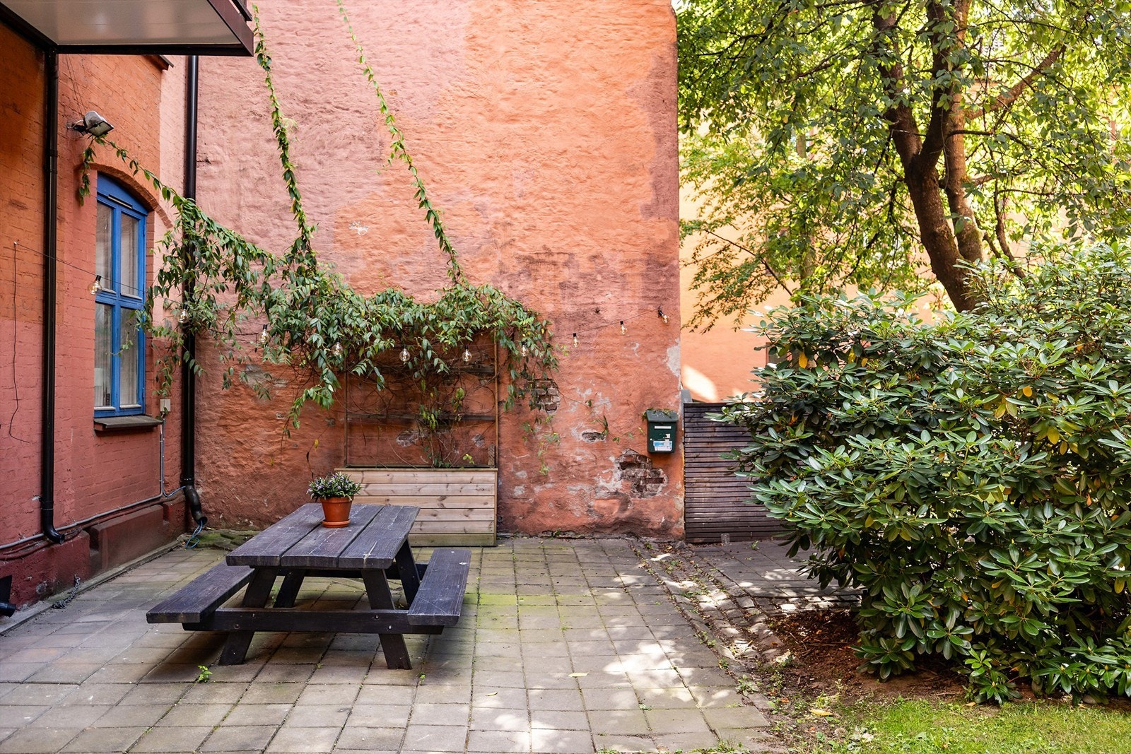 Hyggelig og frodig opparbeidet bakgård med blomsterkasser, benk og lekeapparat og sandkasse. Galleribilde