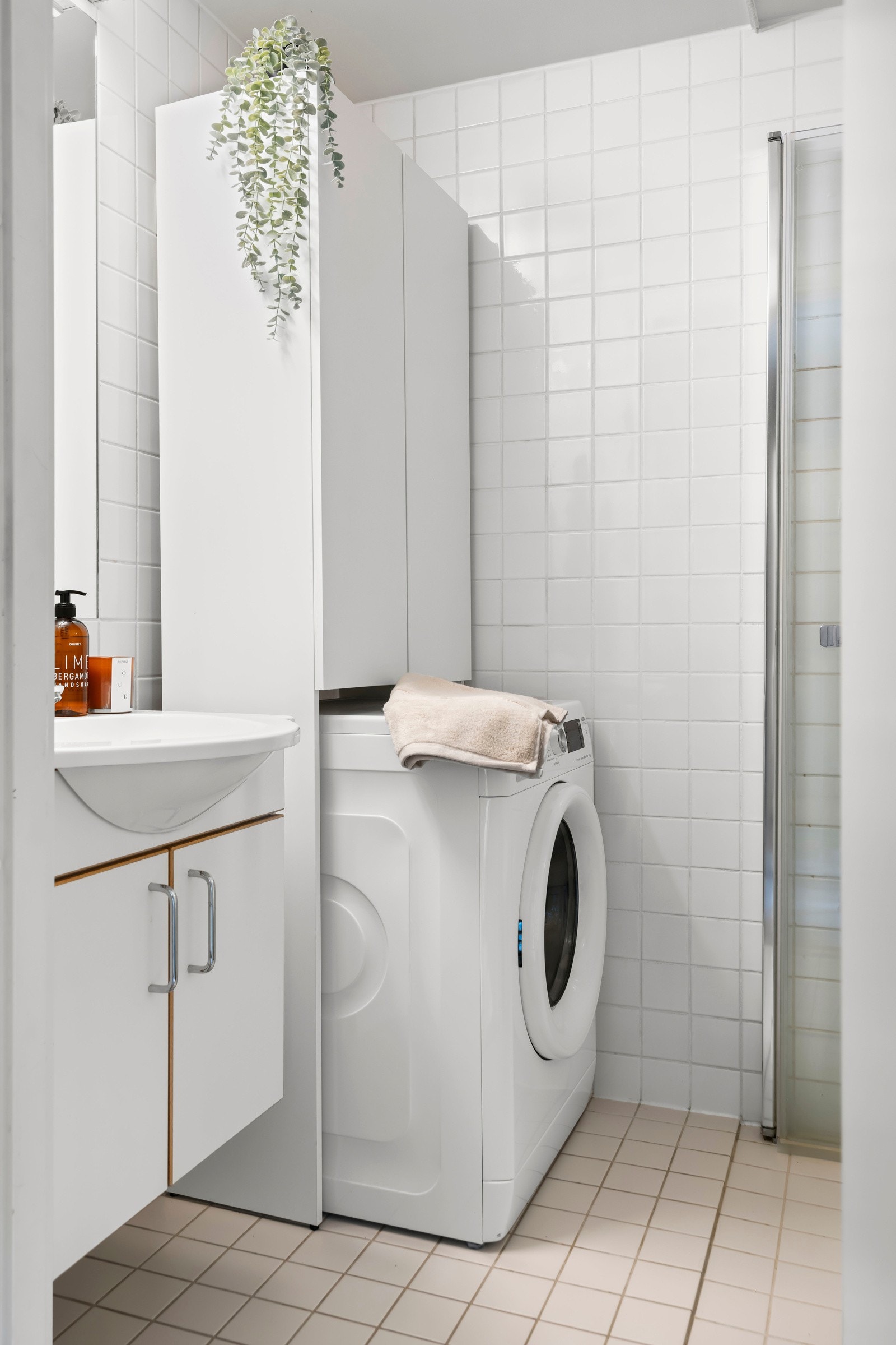 Speil og lysarmatur på vegg over servant. Videre er det dusjhjørne og toalett. Galleribilde