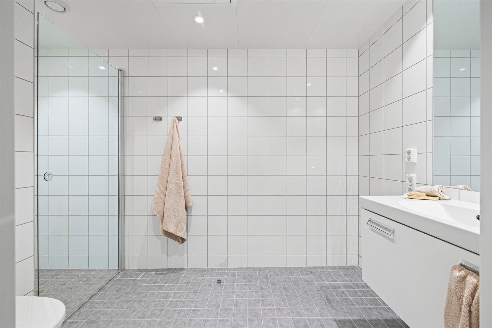 Baderommet inneholder vegghengt toalett, innredning med servant, dusj/vegger og opplegg til vaskemaskin. Galleribilde