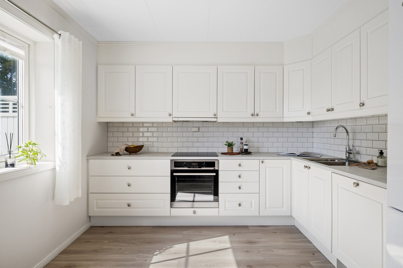 Kjøkkenet har en stilren og klassisk innredning med laminat benkeplate med nedfelt benkebeslag og to kummer, samt delvis, integrerte hvitevarer. Galleribilde